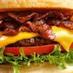 Bacon burger with beef patty on red wooden table