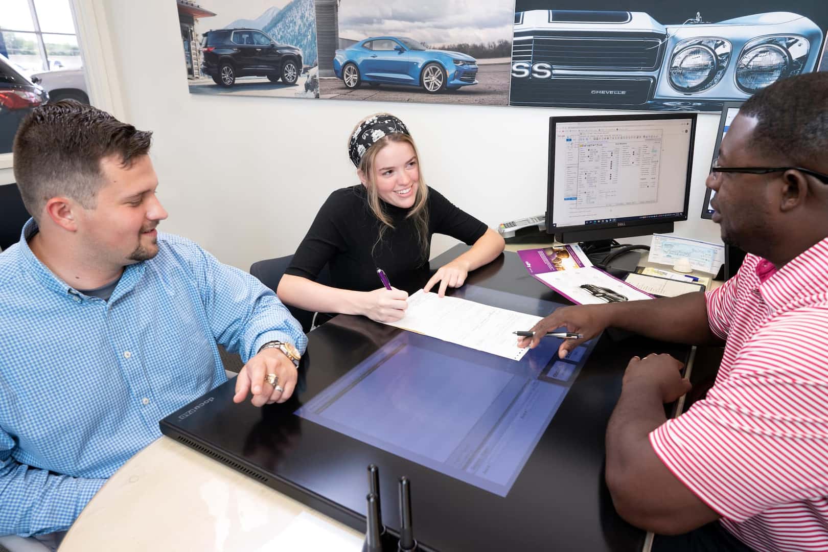 A girl sitting inside a dealership, looking at her computer.