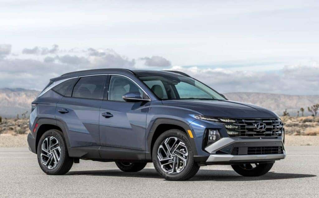 A blue 2024 Hyundai TUCSON parked in front of rolling hills