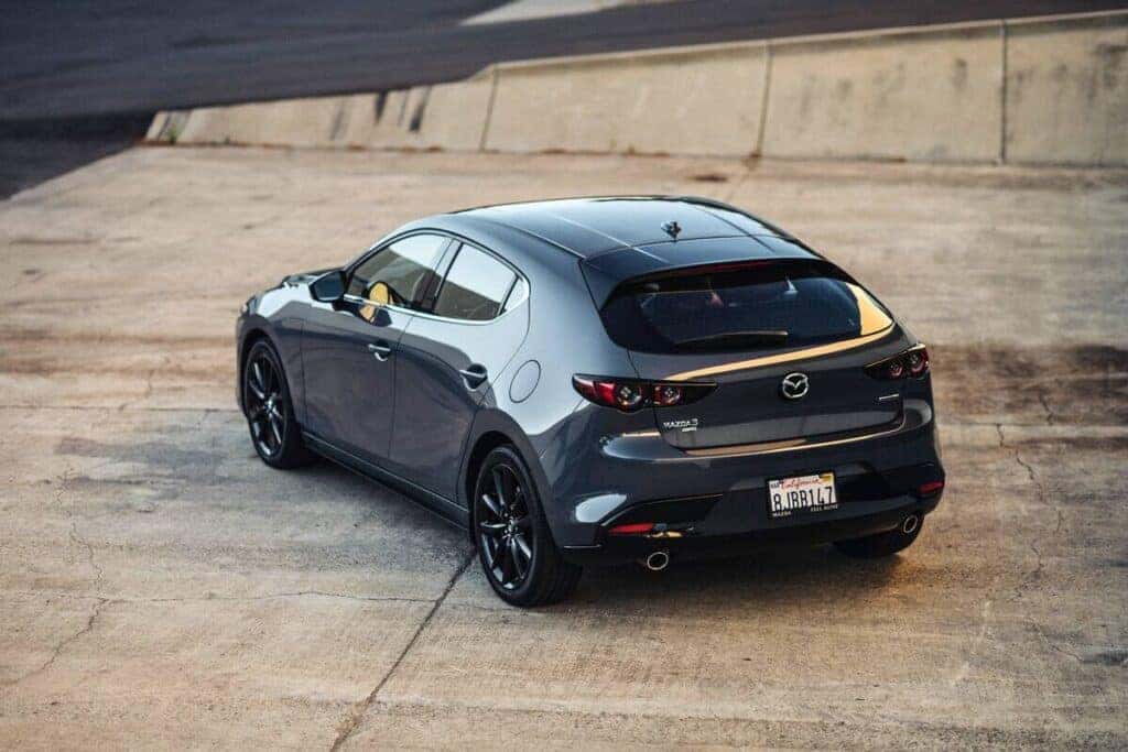 A gray 2025 Mazda3 hatchback viewed from the rear, showcasing its sleek design and distinctive taillights.