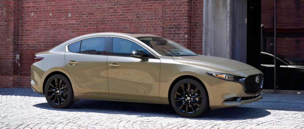 2025 Mazda3 Compact sedan parked in front of a rustic brick bruilding