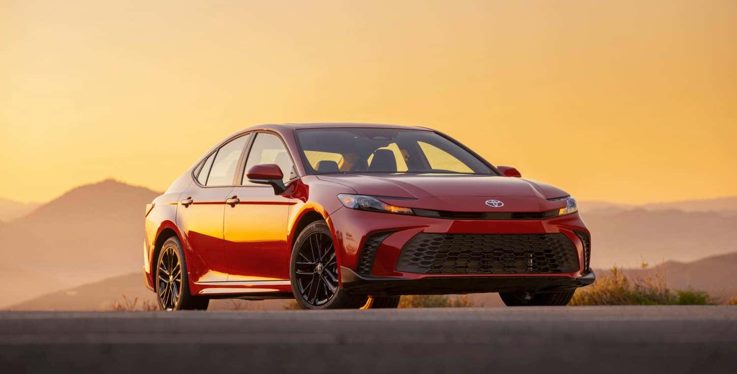 A 2025 Toyota Camry displayed prominently in front of a sunset, showcasing its sleek design and modern features.