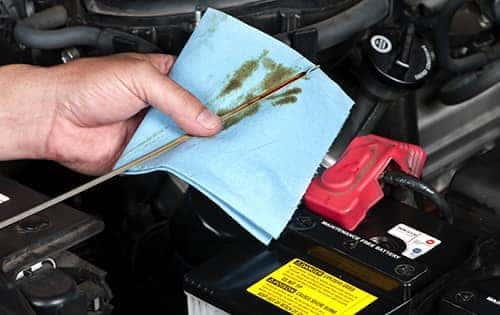 Oil dip stick being wiped onto mechanic towel