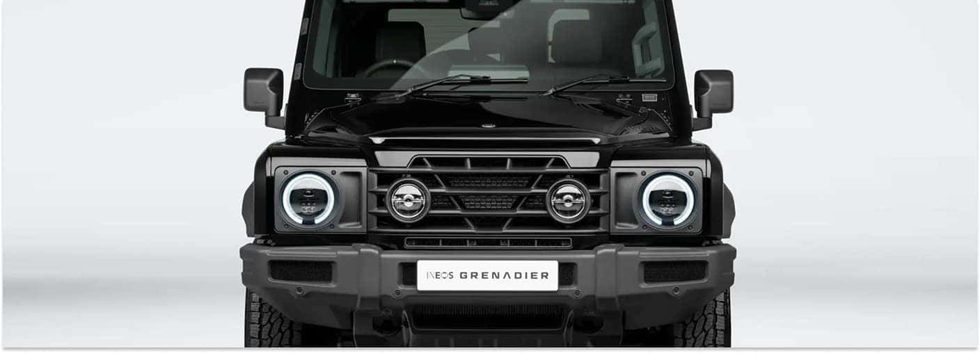 Front view of a black 2026 INEOS Grenadier Black Edition with illuminated headlights in a studio.