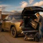 2026 Chevrolet Traverse with rear liftgate open, being loaded with backpacks and sports gear in a Watertown, SD school parking lot