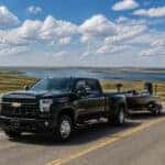 2026 Chevrolet Silverado 3500 HD towing a boat trailer toward Lake Kampeska near Watertown, South Dakota in summer