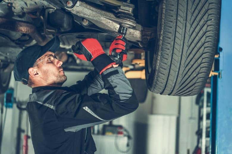 Car Mechanic Adjusting Tension in Vehicle Suspension