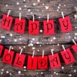 Red Tags with Happy Holidays on it Hanging on a Line on Wood with Snow, Christmas or Winter Holiday Greetings