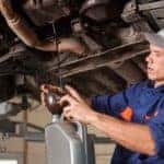 Mechanic draining oil from vehicle