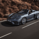 2024 Porsche 718 Spyder RS driving on highway next to mountain