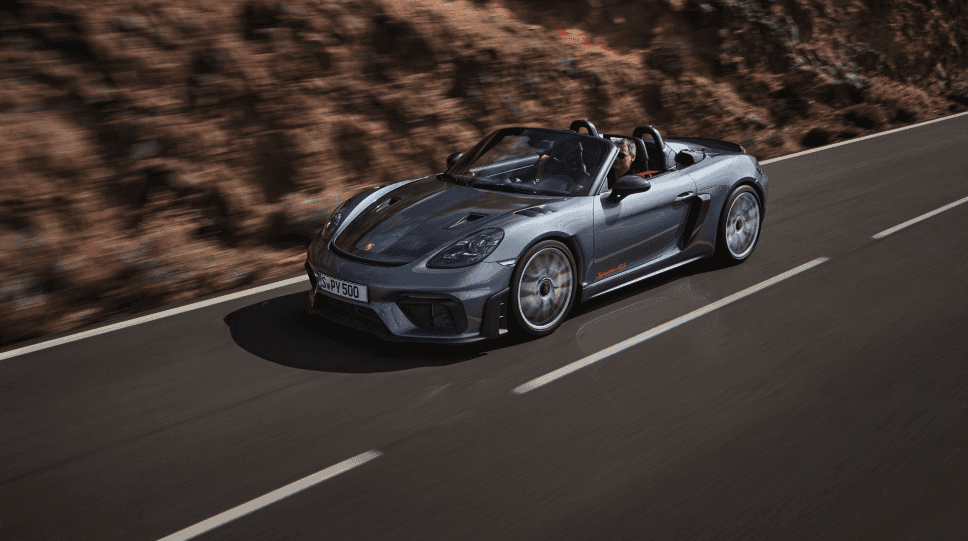2024 Porsche 718 Spyder RS driving on highway next to mountain
