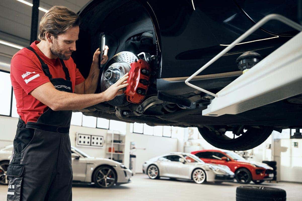 Porsche service technician pouring oil in vehicle