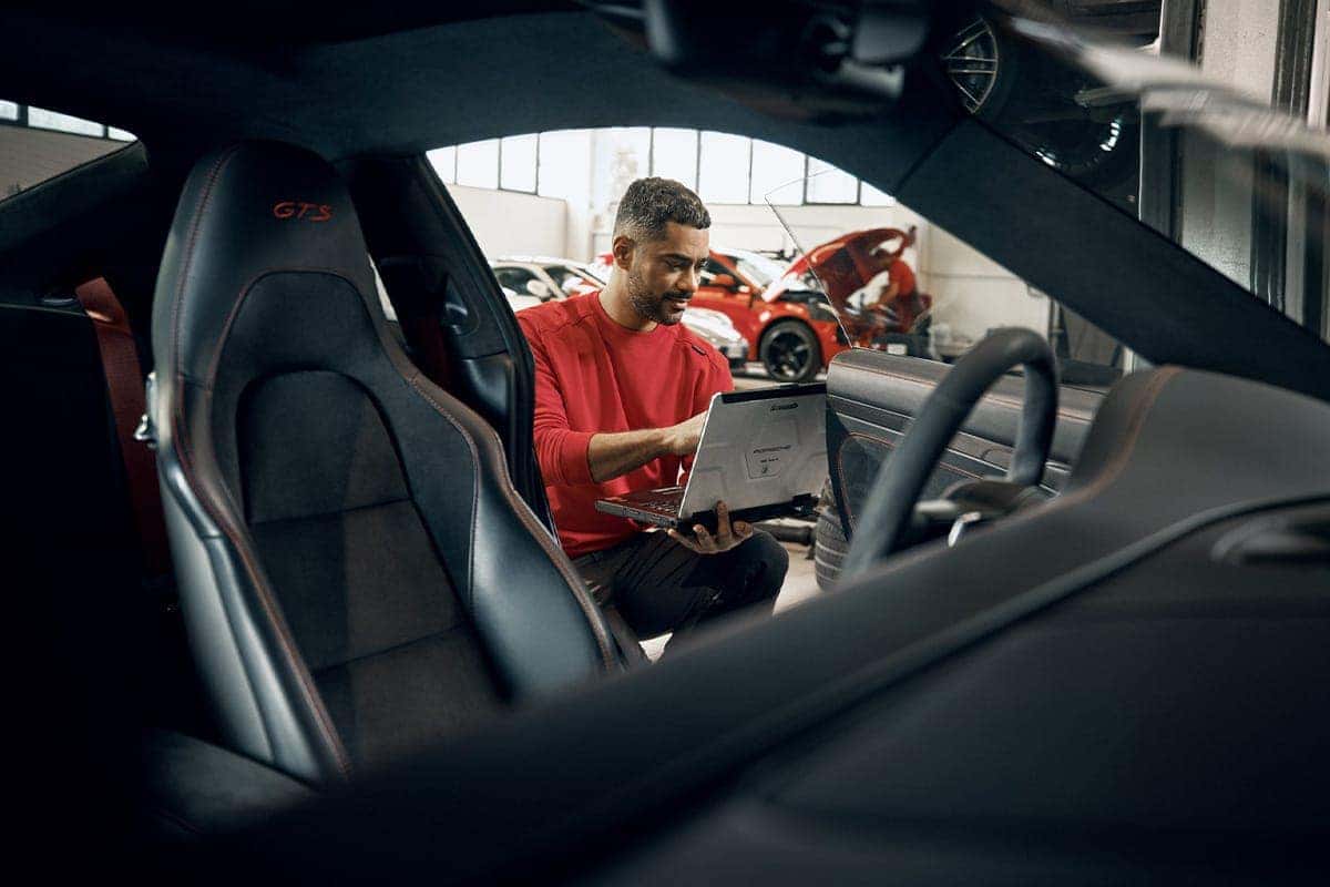 Porsche service technician pouring oil in vehicle